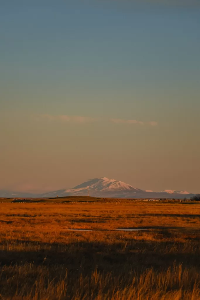 Montagne enneigée au coucher du soleil dans une plaine dorée
