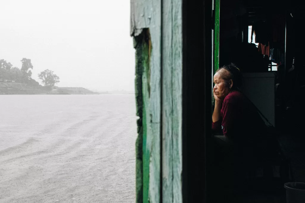 Femme pensive dans l’embrasure d’une maison sous la pluie