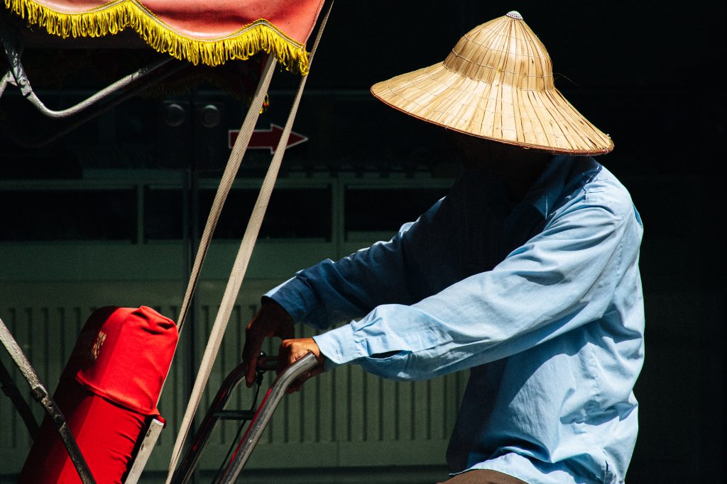 Conducteur vietnamien portant un chapeau conique sur un cyclo-pousse