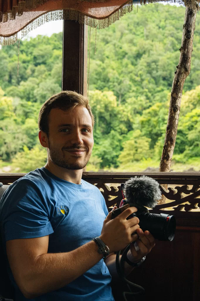 Homme tenant une caméra devant une forêt tropicale