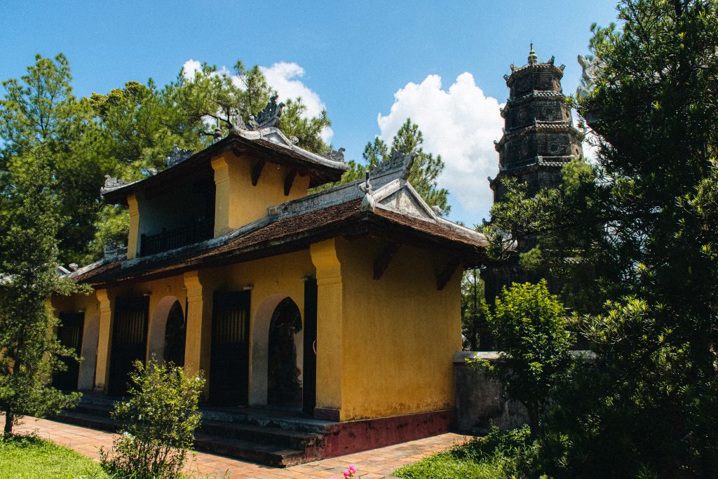 Un paisible temple vietnamien niché dans une végétation luxuriante. Son élégante pagode se détache sur le ciel bleu.