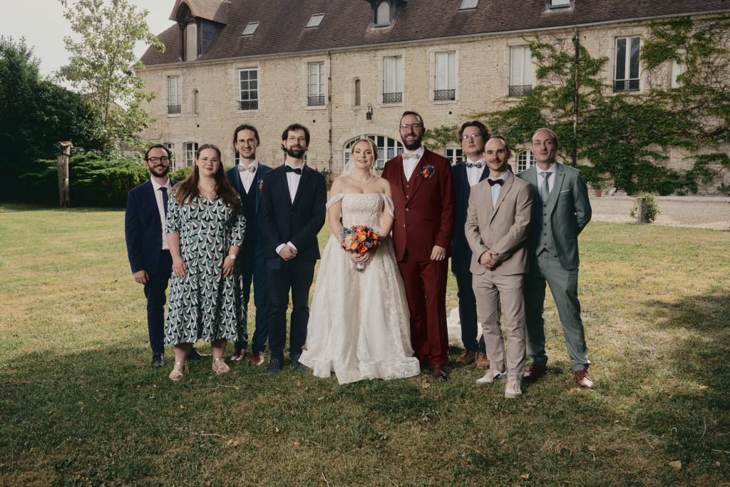 Mariée et invités posant devant une demeure en pierre