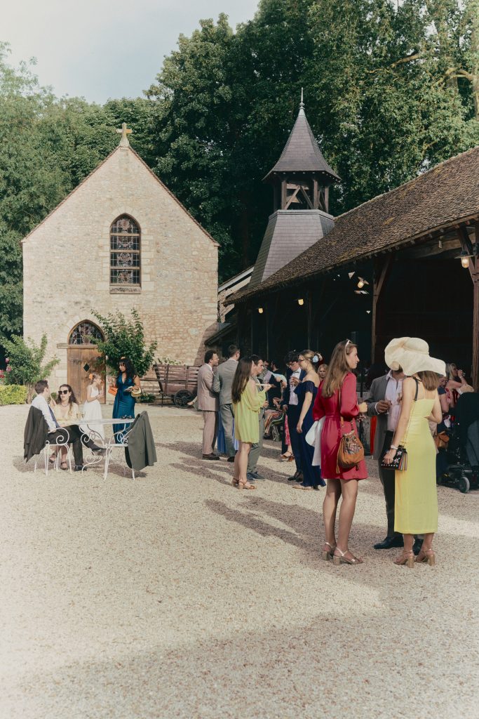 Invités élégants réunis devant une chapelle en pierre