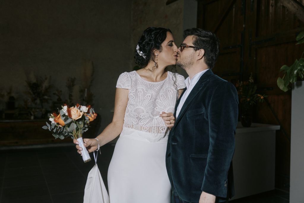 Couple de mariés s’embrassant avec un bouquet de fleurs