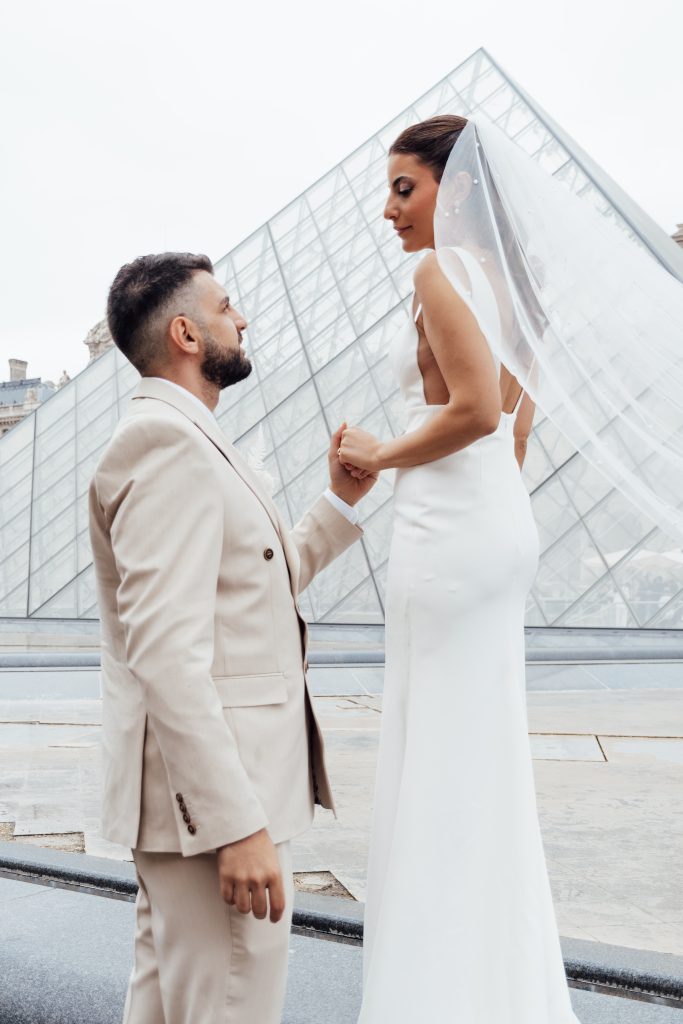 Mariés en tenue blanche sous une verrière moderne