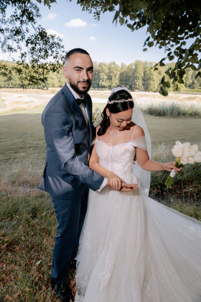 Mariés posant dans un parc, la mariée tenant un bouquet