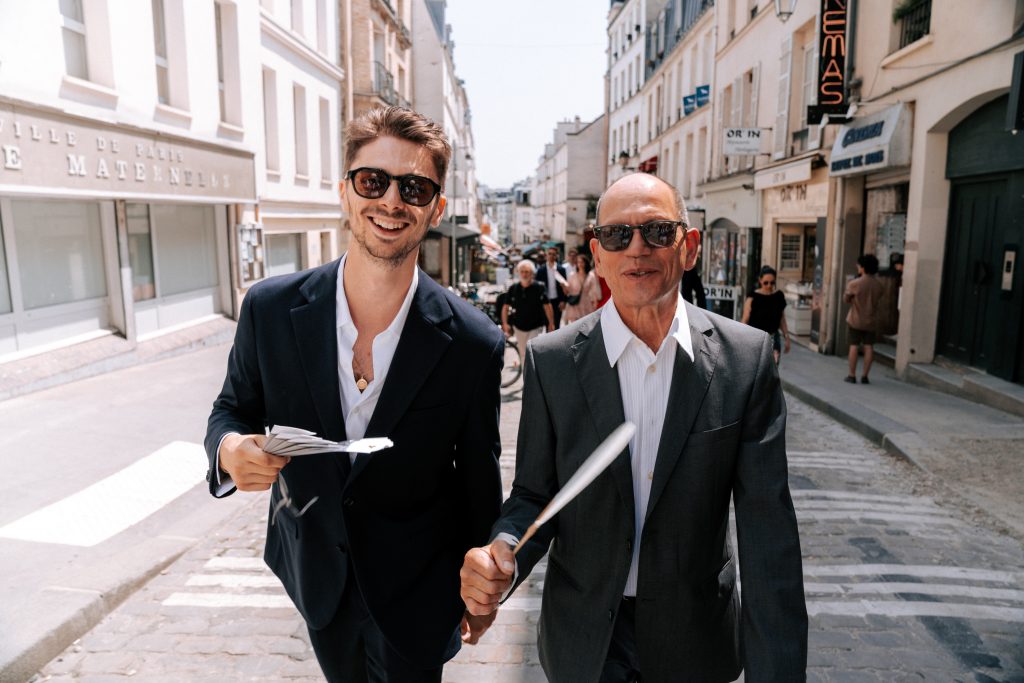 Deux hommes en costume marchent dans une rue parisienne