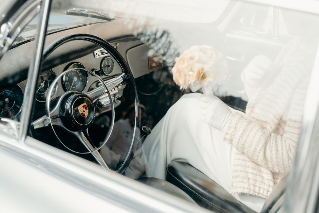 Mariée dans une voiture ancienne, bouquet à la main