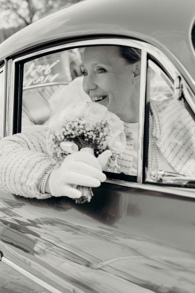 Femme souriante dans une voiture ancienne avec un bouquet