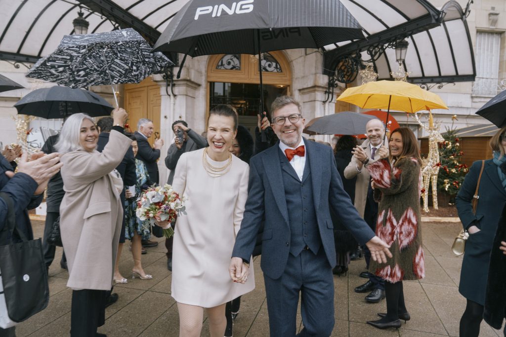 Mariés souriants entourés d’invités sous des parapluies