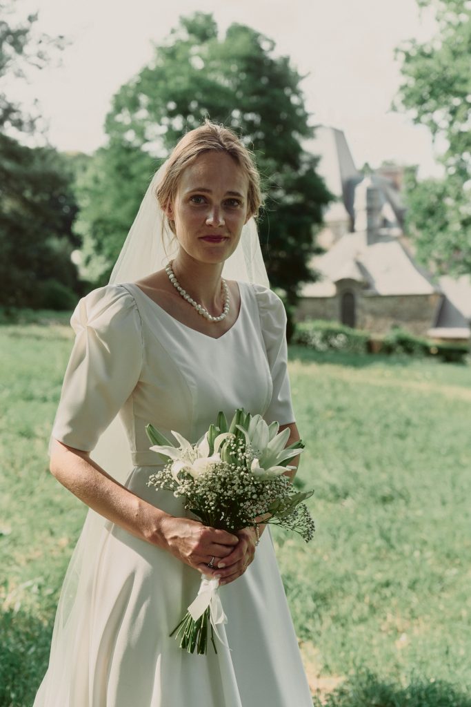 Mariée blonde en robe blanche tenant un bouquet de fleurs